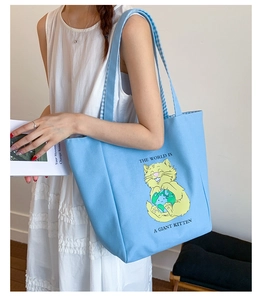 Detail of light blue canvas tote bag with yellow kitten print and blue checkered lining