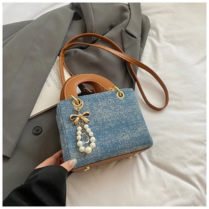 Blue denim texture handbag with brown handles, golden bow and pearl pendant detail