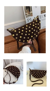 Detail of a brown suede hobo bag with gold metal studs and grommet accents on a marble table