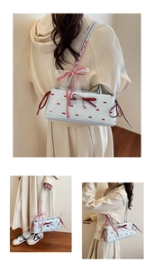 Detail view of light blue baguette bag with red bow prints and delicate lace handle