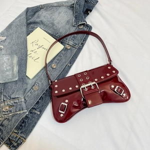 Detailed view of dark red patent leather shoulder bag with silver studs and metal buckles
