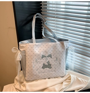 Close-up of light blue polka dot tote bag with lace bows and bunny embroidery detail