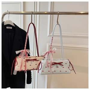 Close-up of bow baguette bag featuring red polka dots and lace ribbon detail on strap
