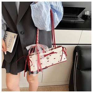 Polka dot shoulder bag detail featuring vintage lace charms and a red ribbon bow