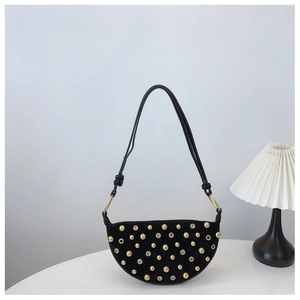 Detail of black suede crescent bag with polished gold studs and punk metal rings