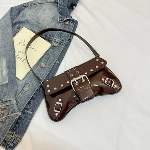 Detail of dark brown patent leather underarm bag with silver rivets and metal buckle