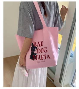 Close-up of pink canvas tote bag featuring dog illustration and red graphic text