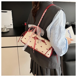 Detail of a creamy white bow shoulder bag with red polka dots and lace ribbon accents