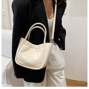 Detailansicht der cremefarbenen Rafftasche mit MAUDAI BEAR Logo und zwei Handgriffen