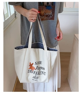 Detail of canvas tote bag showing cute cartoon dog print and blue checkered lining
