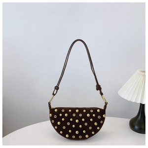 Detail view of dark brown suede half-moon bag with golden rivets and metallic eyelets