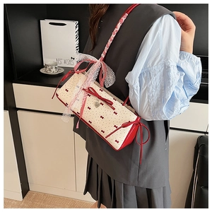 Detail of white lace bow and heart charm on red polka dot shoulder bag with ribbon