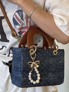 Polka dot denim square tote bag with brown leather handles and pearl bow charm