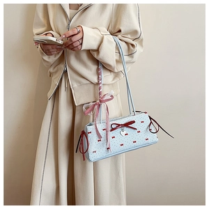 Detail of light blue baguette bag featuring red bow accents and lace ribbon handles
