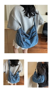Detailed macro view of denim hobo bag featuring multiple zippers and washed blue texture