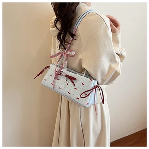 Detail of light blue polka dot baguette bag with lace ribbons and heart pendant