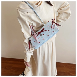 Detail view of light blue shoulder bag with red bow patterns and heart zipper pendant