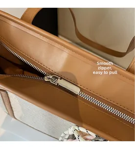 Detail view of the high-quality smooth metal zipper and brown leather trim on the tote bag