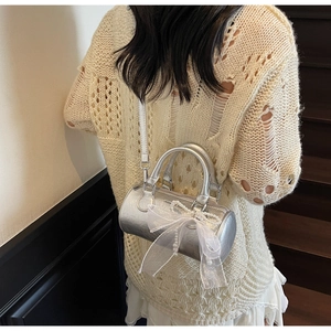 Close-up of silver cylinder pillow bag with lace bow and pearl chain detail on model