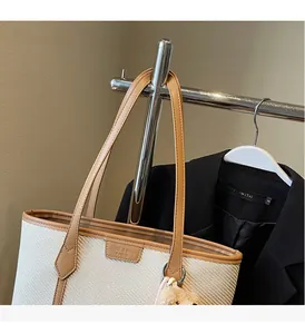 Close-up of beige woven tote bag with brown leather trim and plush charm detail