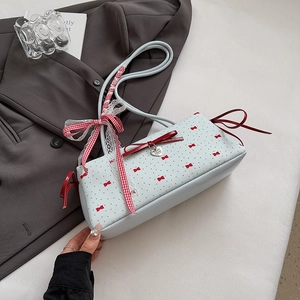 Detail of light blue bow bag with red ribbon, heart pendant and lace trim details