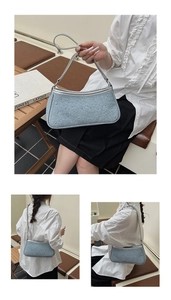 Vista dettagliata della borsa sottobraccio in denim azzurro con borchie argentate e catena