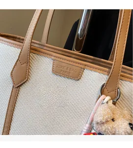 Macro detail of the cream woven fabric texture and brown leather strap on a tote bag