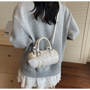 Detail of solid color pillow bag with lace bow and pearl chain in minimalist setting
