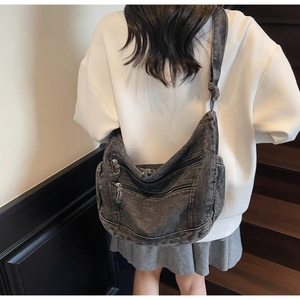 Back view of a model wearing a washed denim crescent crossbody bag with multiple pockets