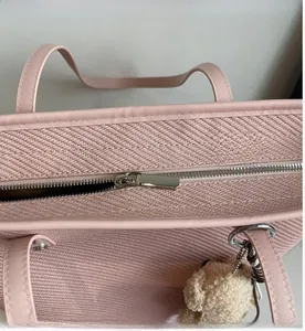 Close-up of pink woven tote bag with smooth metal zipper and plush bear pendant