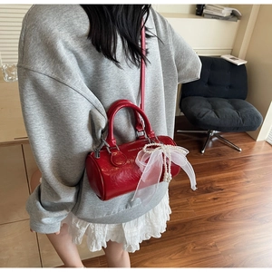 Detail of red patent leather pillow bag with sheer bow and bead accents