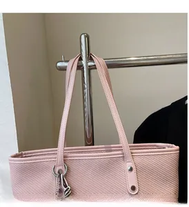 Detail view of pink woven tote bag with leather handle and silver metal hardware