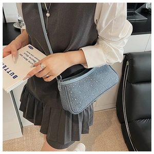 Dettaglio della borsa a spalla in denim azzurro con borchie argentate e forma baguette retrò