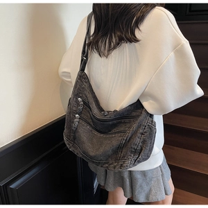 Detail view of large denim hobo bag featuring multiple zip pockets and vintage wash