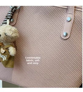 Close-up of pink woven tote bag with silver rivets and a cute plush puppy charm