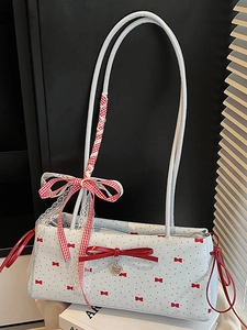 Blue Boston bag with red bow prints and heart pendant shown in a cozy indoor setting