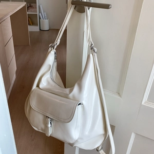 Close-up of cream PU leather tote bag with front flap pocket hanging on door