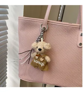 Close-up of teddy bear plush charm with corduroy overalls on a pink tote bag