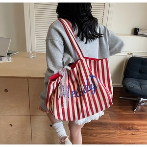 Détail du sac en toile à rayures rouges avec broderie melody et nœud en dentelle