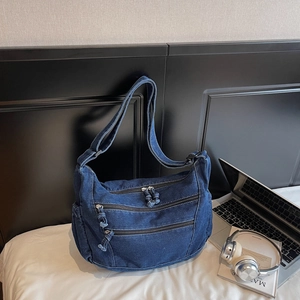 Close-up of durable denim crossbody bag with multiple zippers and wide adjustable strap