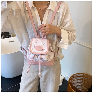 Detail eines geblümten Mini-Rucksacks mit rosa Trägern und süßen Tiermustern am Modell