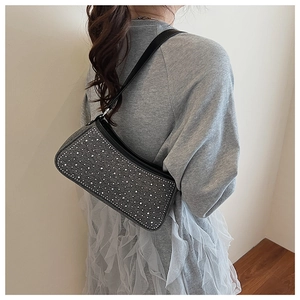 Vista dettagliata di una borsa baguette nera con strass sulla spalla di una modella