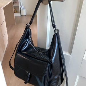 Detail view of glossy black oil-wax leather tote with functional buckle strap