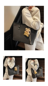 Detail of black textured tote bag featuring a cute bear pendant on wooden stairs