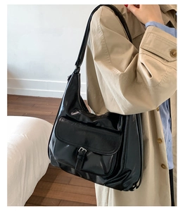 Close-up of black glossy PU leather tote bag with silver magnetic buckle and zipper details