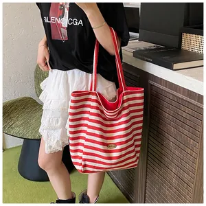 Vue détaillée d'un grand sac fourre-tout en toile à rayures rouges et blanches avec plaque en métal