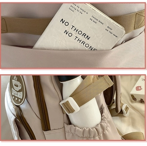 Detail view of pink nylon backpack featuring side pockets and round coffee break badge