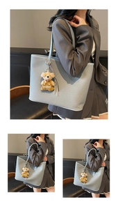 Close-up of light blue woven tote bag with cute bear charm and thin shoulder straps