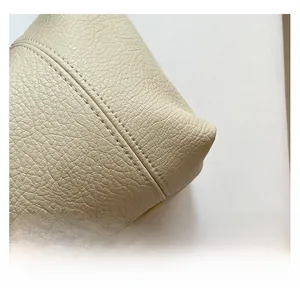 Close-up of beige leather baguette bag showing fine pebble texture and precise stitching