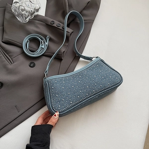 Dettaglio borsa a tracolla in denim azzurro con borchie argento e doppi spallacci